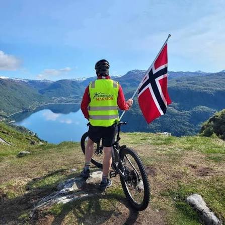 Deltaker med det norske flagget på fjelltopp med utsikt over fjorden